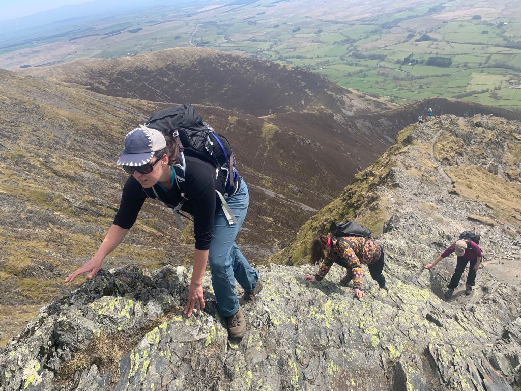 Couple scrambling steep rocky ridge