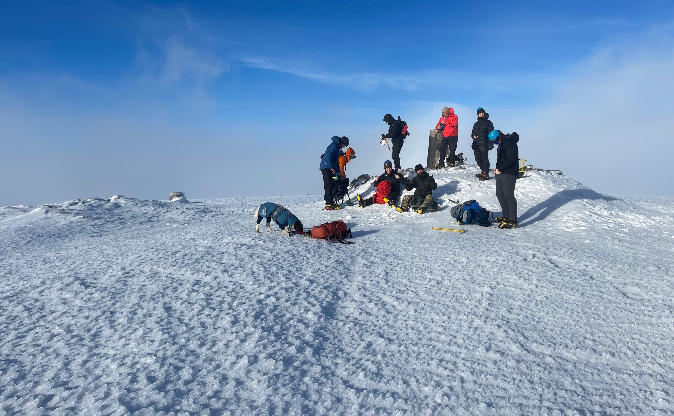 hikers on snowy mountain summit with blue sky