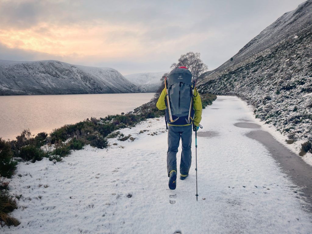 solo hiker with ice axe next to lake